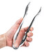 A person holding a pair of silver plastic serving tongs.