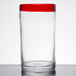 A clear Libbey cooler glass with a red rim on a table.