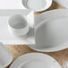 A group of Tuxton Pacifica bright white bowls with an embossed rim.