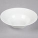 A Tuxton bright white china soup bowl with an embossed white rim on a white surface.