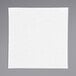 A white square linen-feel dinner napkin on a white surface.