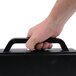 A hand holding a black carrying case with a handle.