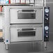 Two Waring countertop pizza ovens on a stainless steel counter.