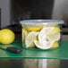 A Carlisle clear plastic crock filled with lemons and a knife.