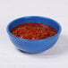 An Elite Global Solutions blue speckle bowl filled with red chili on a white table.