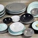 A stack of mint green irregular round melamine plates on a wood surface.