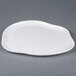 An Elite Global Solutions white melamine plate with a curved, irregular edge.