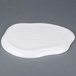 A white Elite Global Solutions melamine plate with an irregular edge on a gray surface.