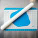 A blue and white dough rolling pin with grid measurements on a white silicone baking mat.
