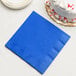 A Creative Converting cobalt blue paper dinner napkin next to a white cake.