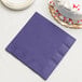 A purple Creative Converting paper dinner napkin on a stack of white plates.