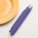 A purple Creative Converting paper dinner napkin with a fork and knife in it.