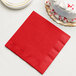 A red Creative Converting paper dinner napkin next to a white cake.