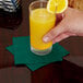 A hand holding a glass of orange juice with a slice of lemon on the rim.