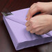 A person wrapping a Luscious Lavender purple napkin around silverware.