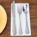 A white Creative Converting guest towel with silverware on a yellow plate.
