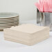 A stack of ivory Creative Converting luncheon napkins.