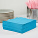 A stack of turquoise blue Creative Converting luncheon napkins.
