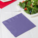 A purple 2-ply luncheon napkin with a fork and salad on a plate.