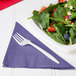 A plate of salad with strawberries, spinach and blueberries with a purple Creative Converting 2-ply luncheon napkin on a white background.