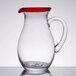 A clear glass pitcher with a red rim and handle.