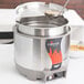 A Vollrath round countertop soup warmer with a ladle in it.