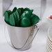 A bucket filled with hunter green plastic spoons.