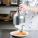 A chef using a Cres Cor infrared bulb to warm food on a white plate.