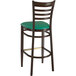 A Lancaster Table & Seating metal ladder back bar stool with green vinyl seat and back.