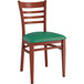 A Lancaster Table & Seating metal ladder back chair with mahogany wood grain finish and green vinyl seat.