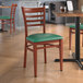 A Lancaster Table & Seating green vinyl chair with mahogany wood grain finish and metal ladder back.