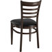 A Lancaster Table & Seating metal ladder back chair with dark walnut wood grain finish and black vinyl seat.