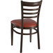 A Lancaster Table & Seating metal ladder back chair with dark walnut wood grain finish and burgundy vinyl seat.
