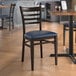 A Lancaster Table & Seating metal ladder back chair with a detached navy vinyl seat.