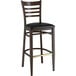 A Lancaster Table & Seating restaurant bar stool with a wooden frame and black seat.