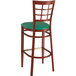 A Lancaster Table & Seating metal bar stool with a green vinyl seat and mahogany wood grain finish.