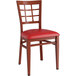 A Lancaster Table & Seating Spartan Series red metal chair with mahogany wood grain finish and red vinyl seat.