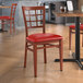 A Lancaster Table & Seating red vinyl chair with mahogany wood grain finish at a table in a restaurant.