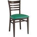 A Lancaster Table & Seating metal ladder back chair with dark walnut wood grain finish and a green vinyl seat.