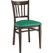 A Lancaster Table & Seating metal chair with dark walnut wood grain finish and green vinyl seat and back.
