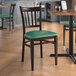 A Lancaster Table & Seating chair with a green vinyl seat and metal frame.
