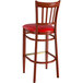 A wooden bar stool with a red vinyl cushion.