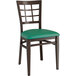 A Lancaster Table & Seating Spartan Series metal chair with dark wood frame and green vinyl seat.