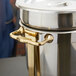 A gold metal side handle for a Vollrath soup chafer.
