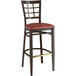 A Lancaster Table & Seating metal bar stool with a burgundy vinyl seat and dark walnut wood grain finish.
