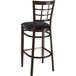 A Lancaster Table & Seating Spartan Series metal bar stool with a black cushion and wood grain finish.