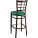 A Lancaster Table & Seating metal bar stool with a green vinyl seat and a window back.