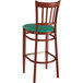 A Lancaster Table & Seating Spartan Series wooden bar stool with green vinyl seat.