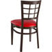 A Lancaster Table & Seating metal window back chair with a dark walnut wood grain finish and red vinyl seat.