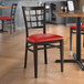A Lancaster Table & Seating metal chair with dark walnut wood grain finish and red vinyl seat.
